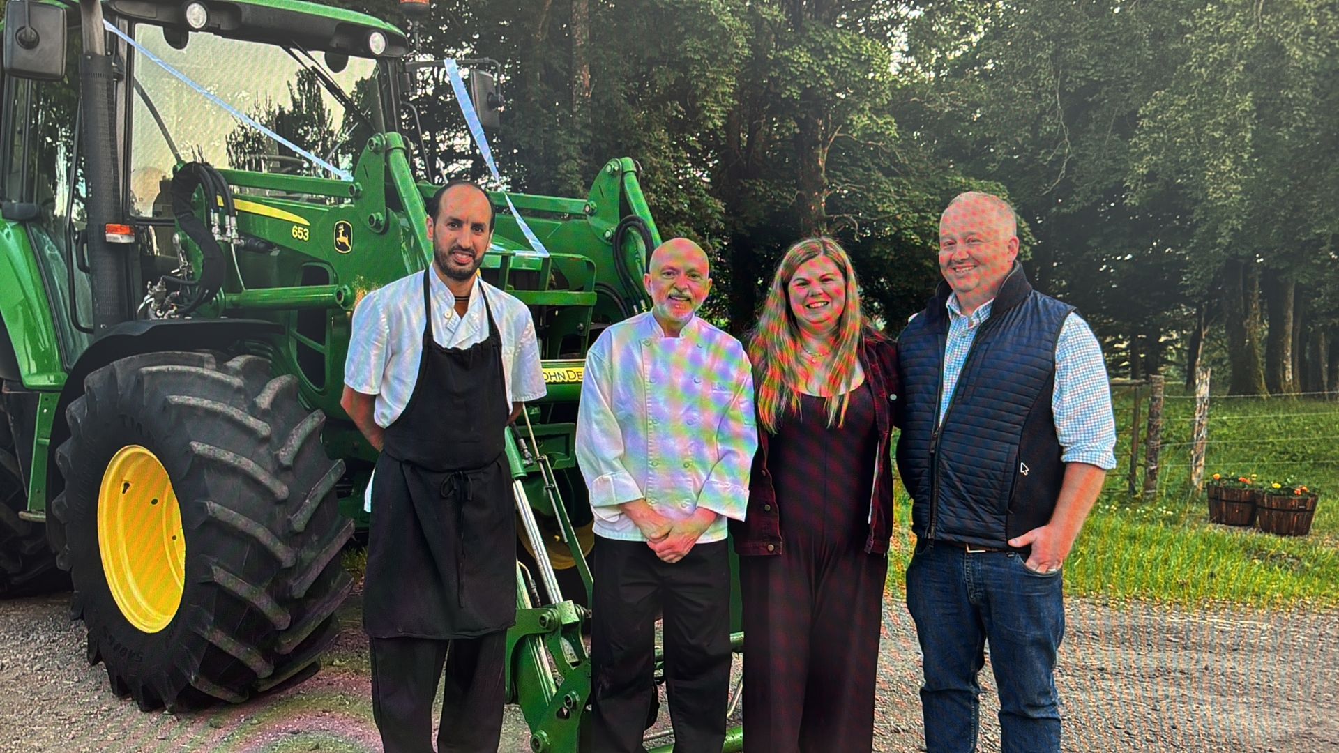 Private chef Giuseppe Manzoli and his head chef with the newly married couple beside a ribbon-decorated John Deere tractor after a two-day wedding weekend on an estate in Angus
