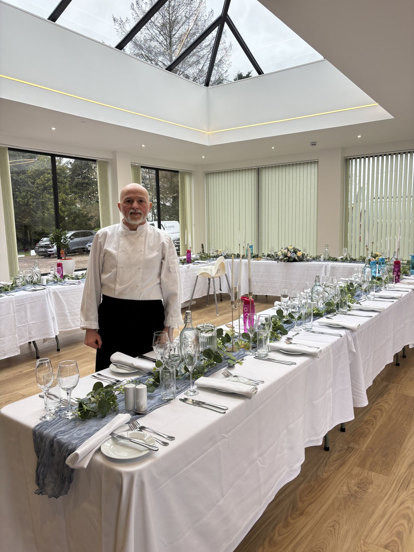 Italian private chef Giuseppe Manzoli beside a long wedding table set for dinner in a Scottish venue