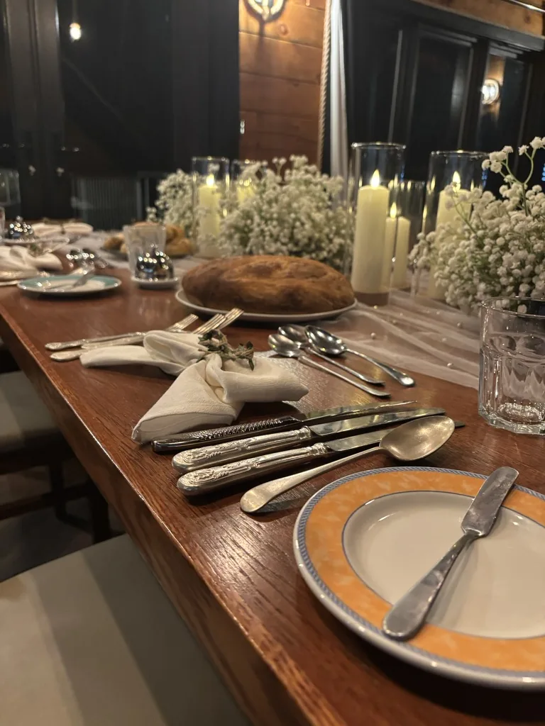 Candlelit table with white flowers and homemade bread for a pre-wedding dinner at Loch Ness