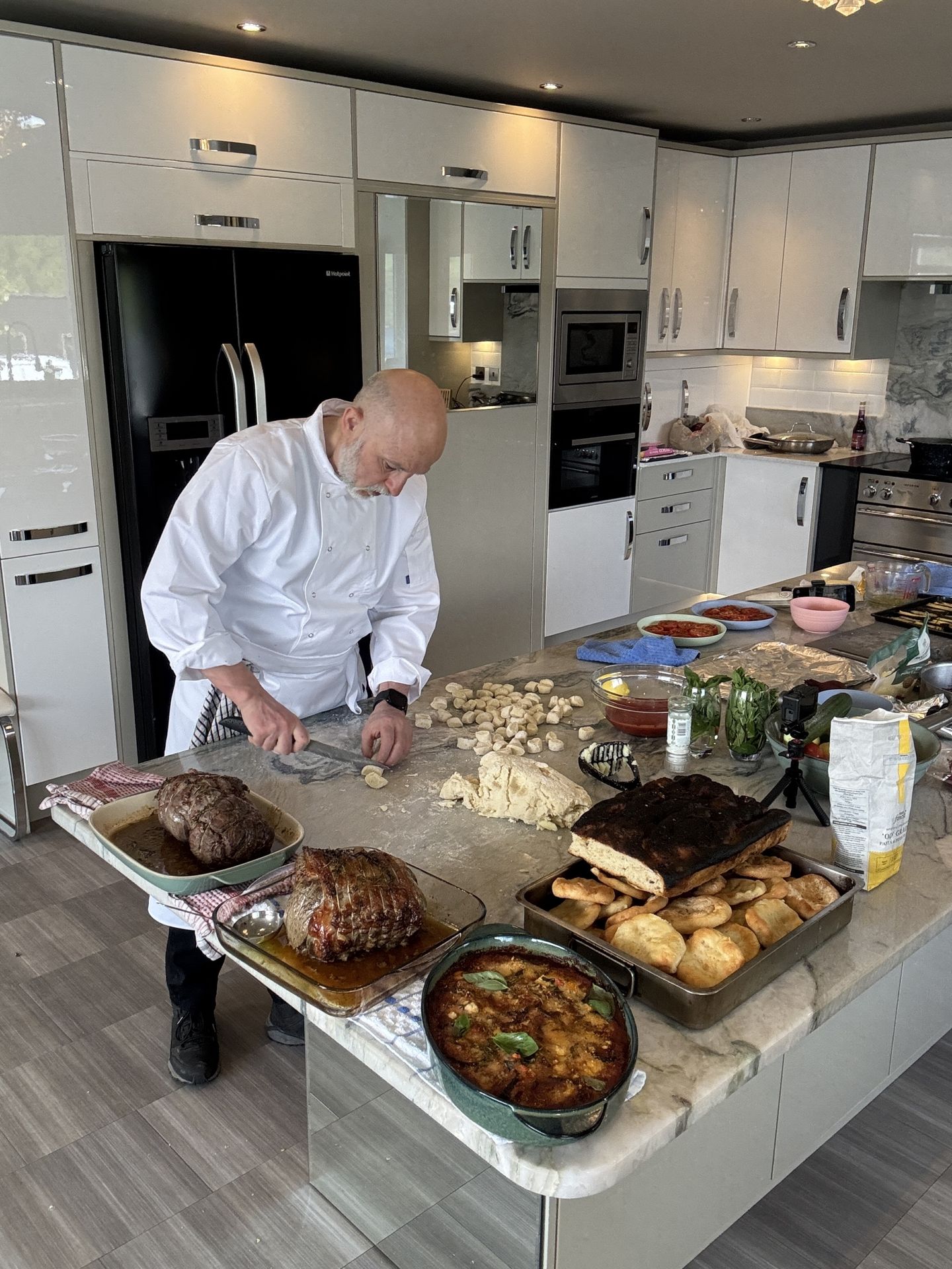 Giuseppe Manzoli in chef whites rolling fresh gnocchi by hand in a private kitchen.