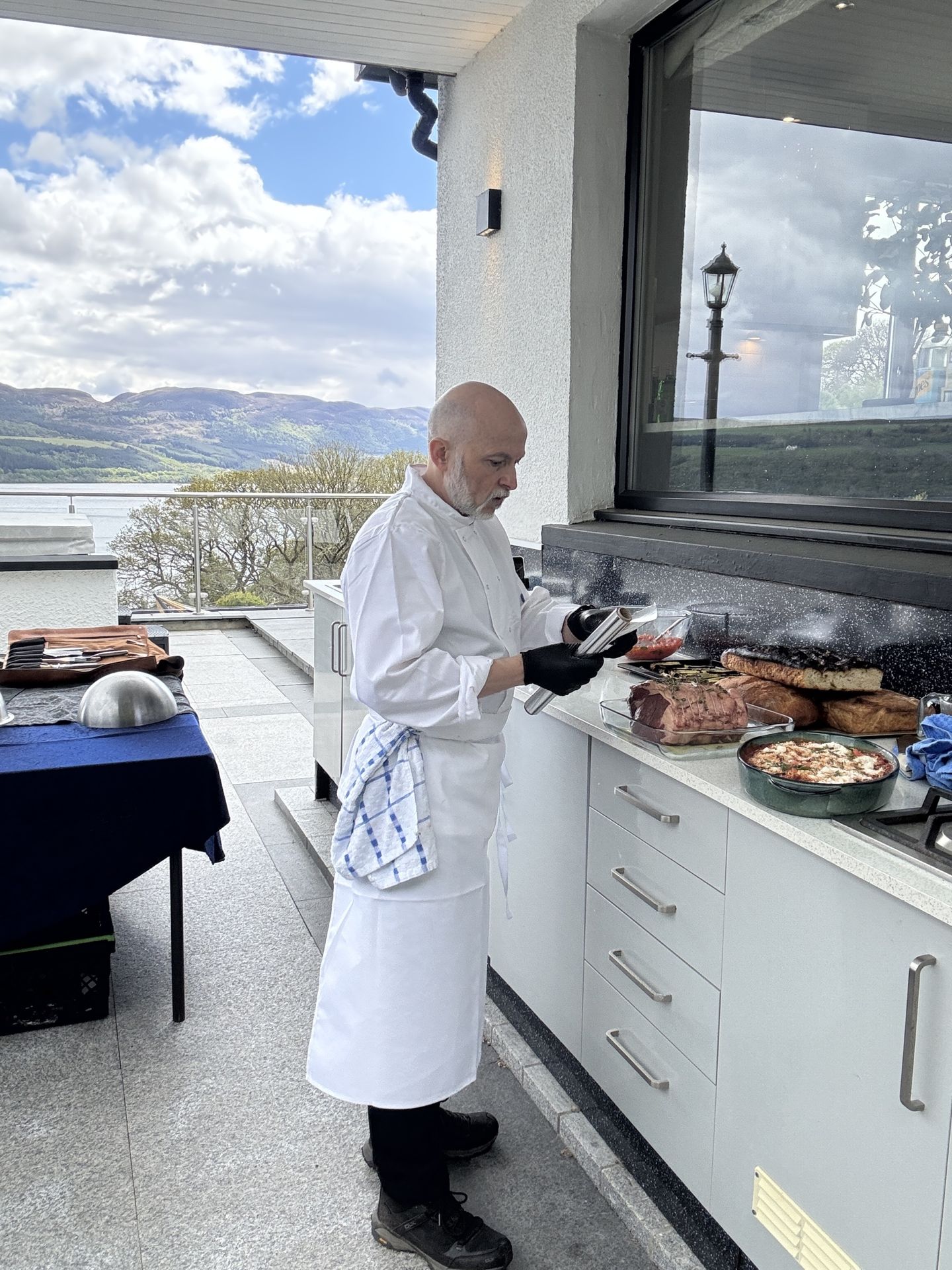 Giuseppe Manzoli in chef whites preparing food at an outdoor kitchen.