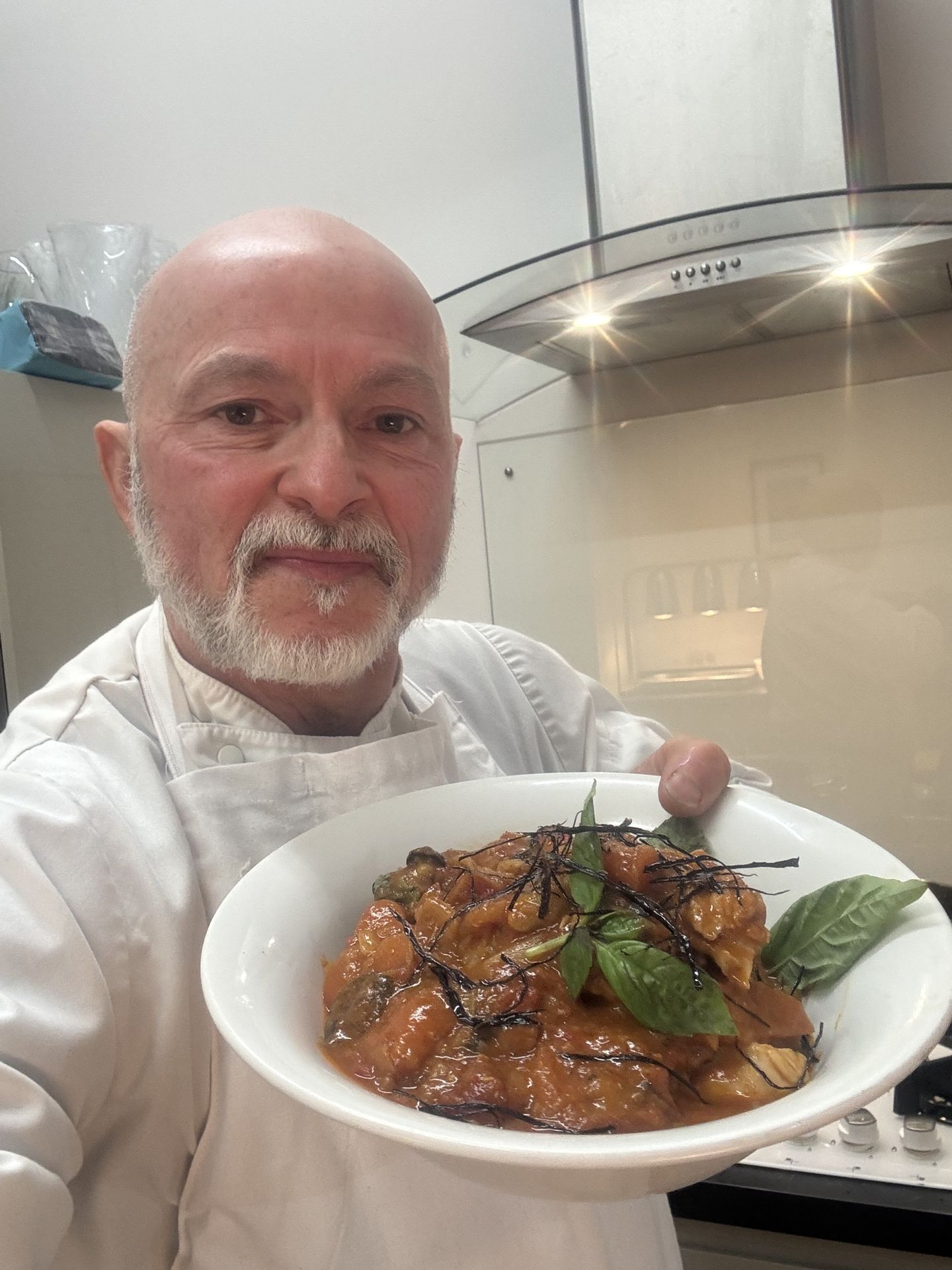 Private chef Giuseppe Manzoli holding a plate of homemade ravioli marinara — Italian cooking across Scotland
