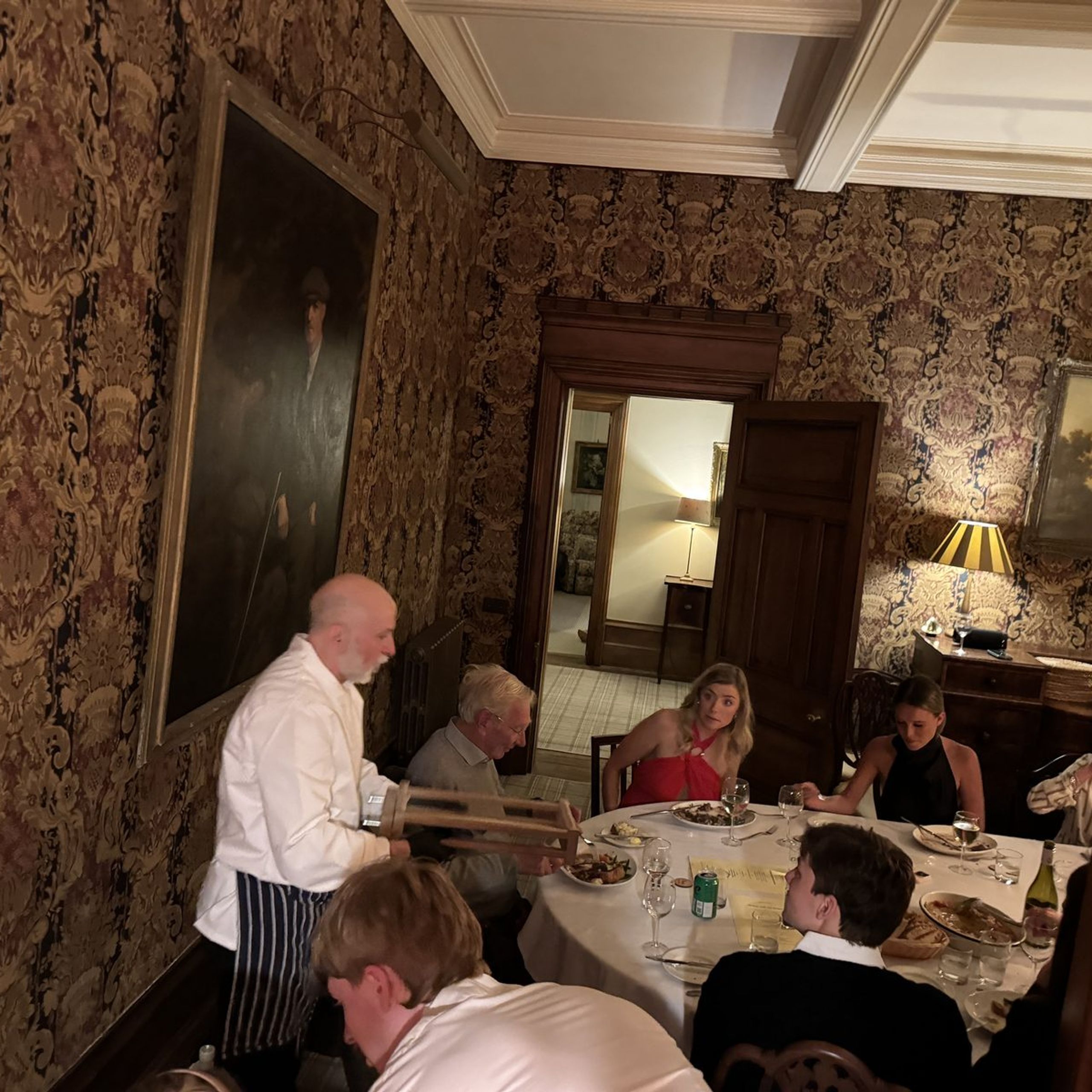 Giuseppe Manzoli carving at the table while guests watch, at a country house dinner in Scotland