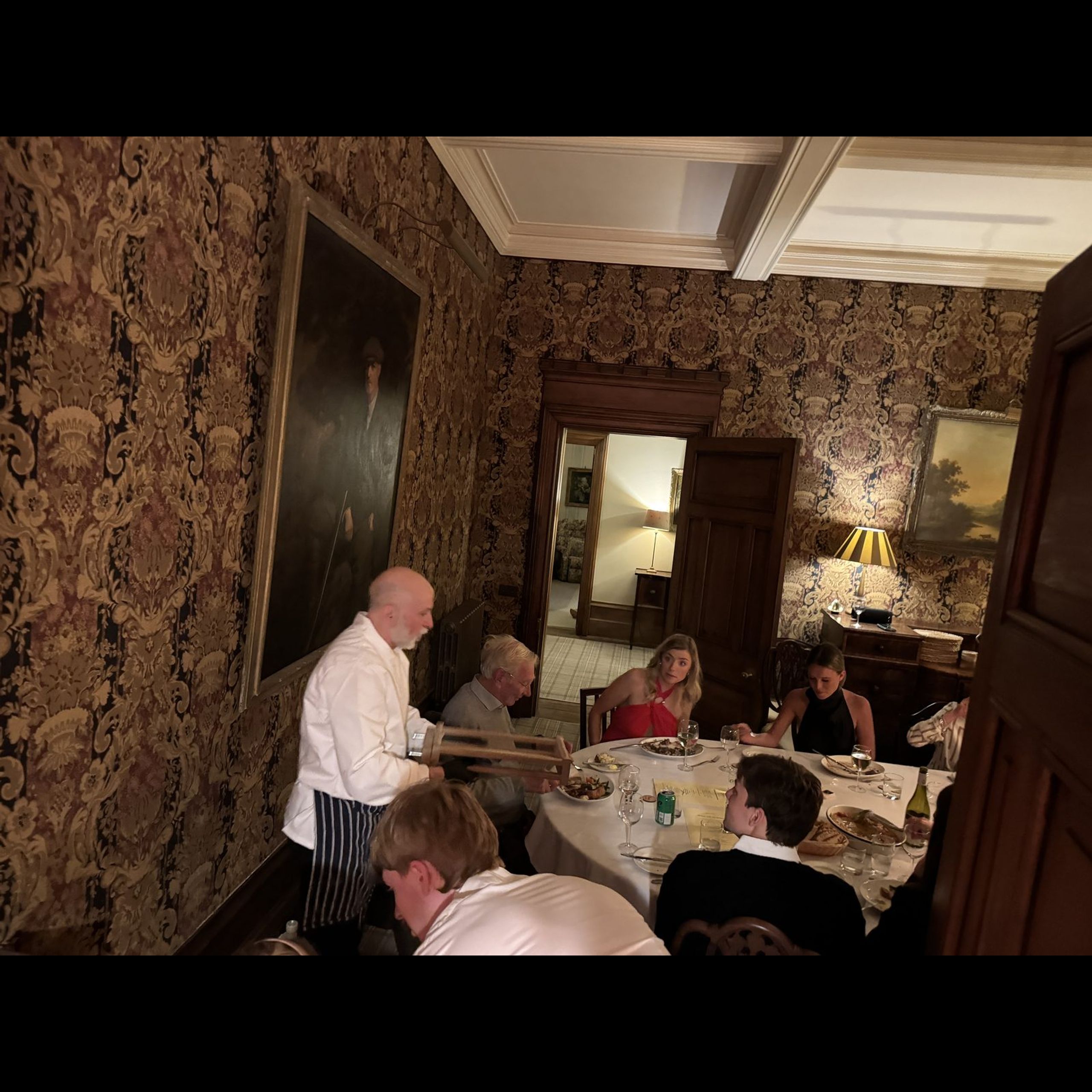 Giuseppe Manzoli carving at the table while guests watch, at a country house dinner in Scotland