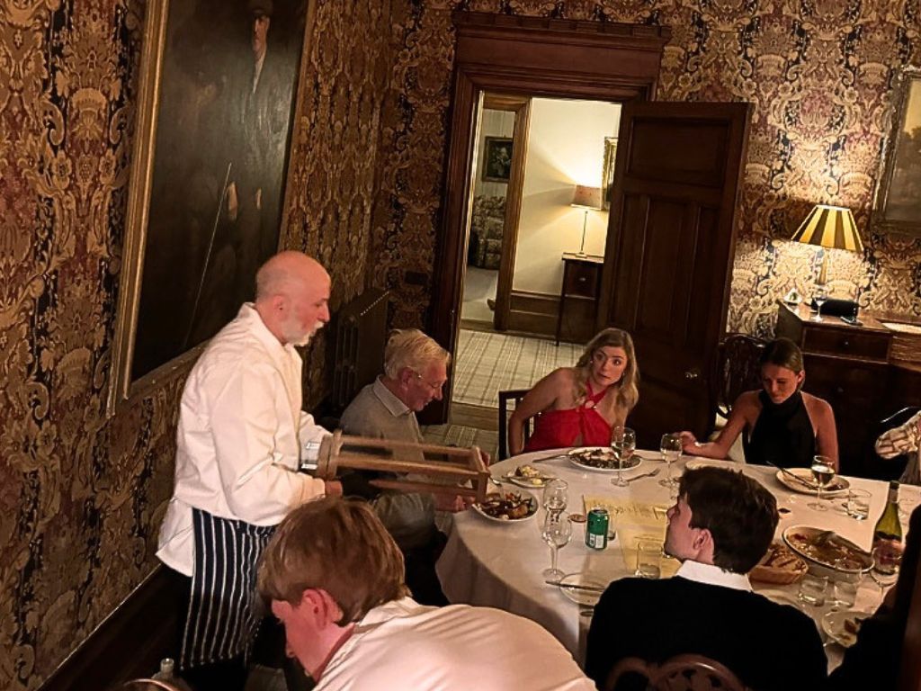 Private chef Giuseppe Manzoli cutting fresh pasta on a chitarra at a candlelit dinner in a Scottish country house dining room
