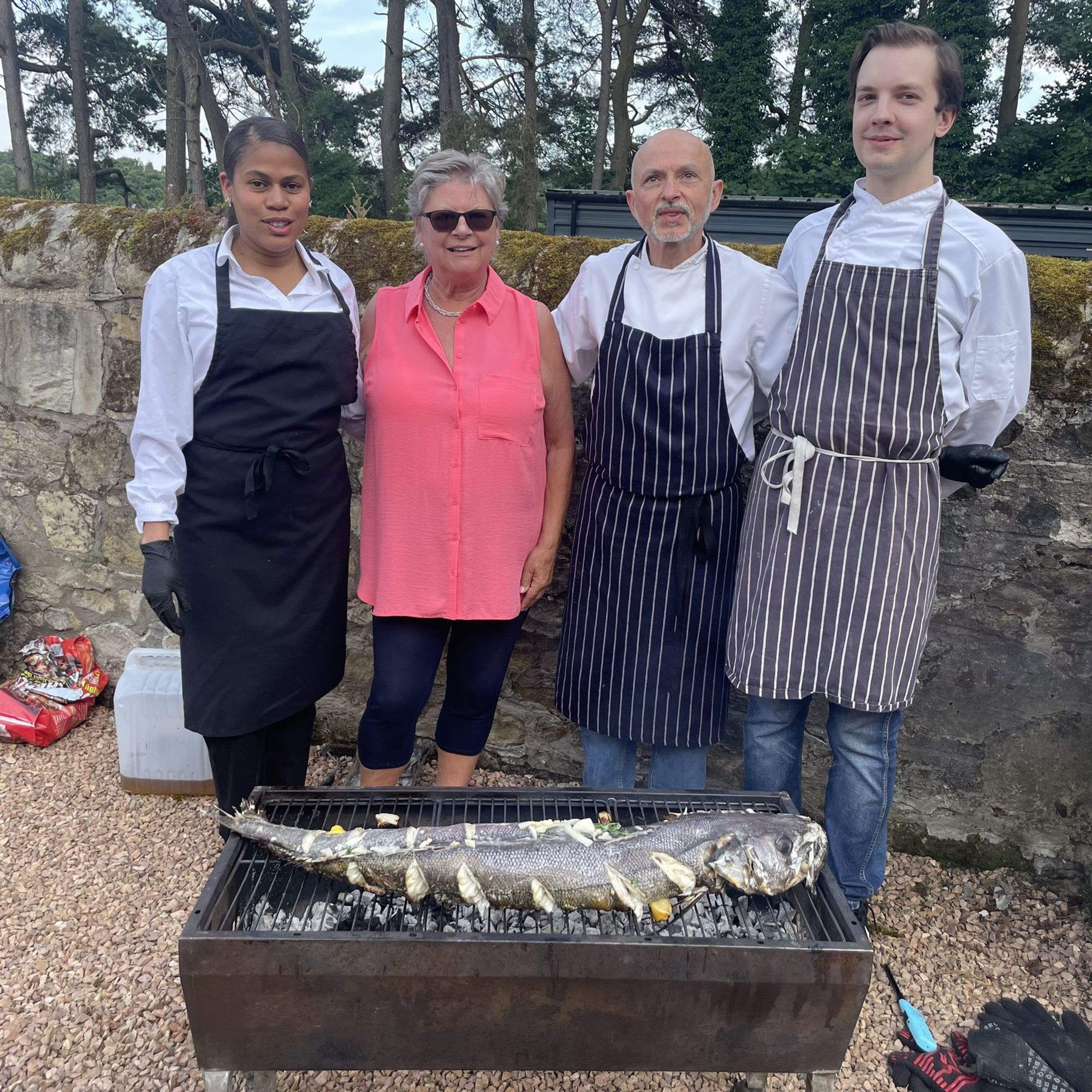 Whole sea bass cooking over charcoal at Burgie House, Forres, with Giuseppe Manzoli and his team