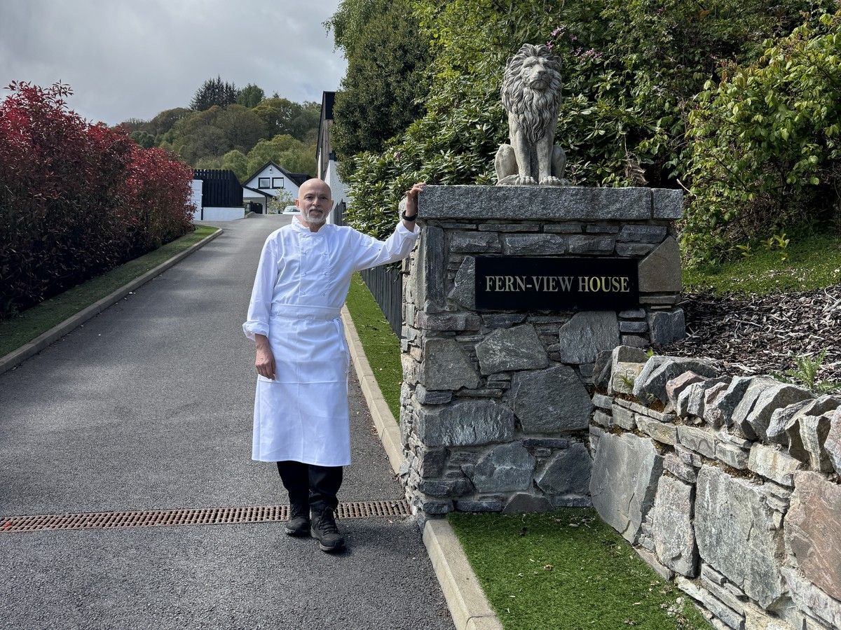 Giuseppe Manzoli, Italian private chef, beside the stone entrance sign for Fern View House near Loch Ness in the Scottish Highlands