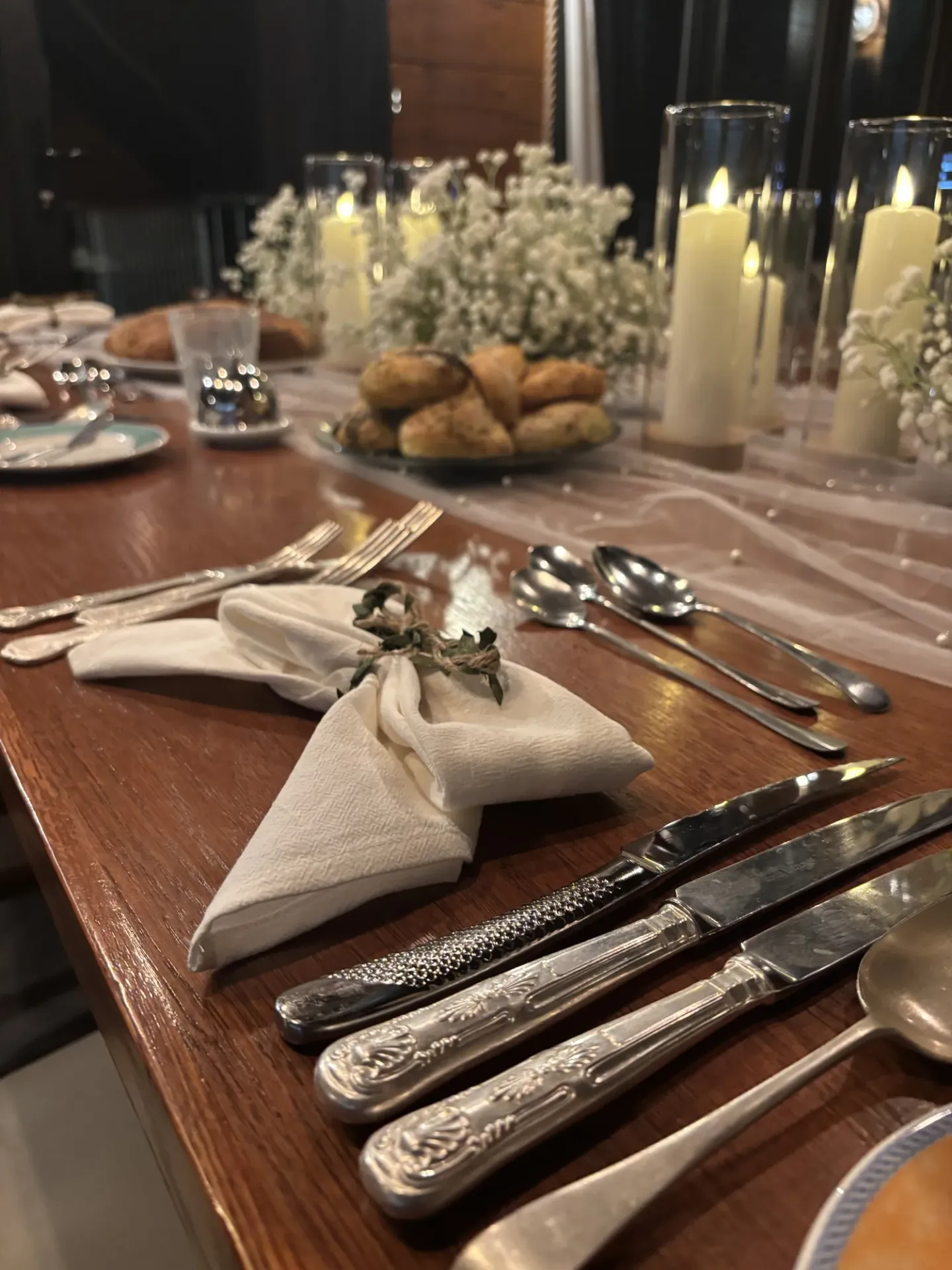 Pre-wedding dinner table with candles, white flowers and freshly baked bread at a Loch Ness lodge