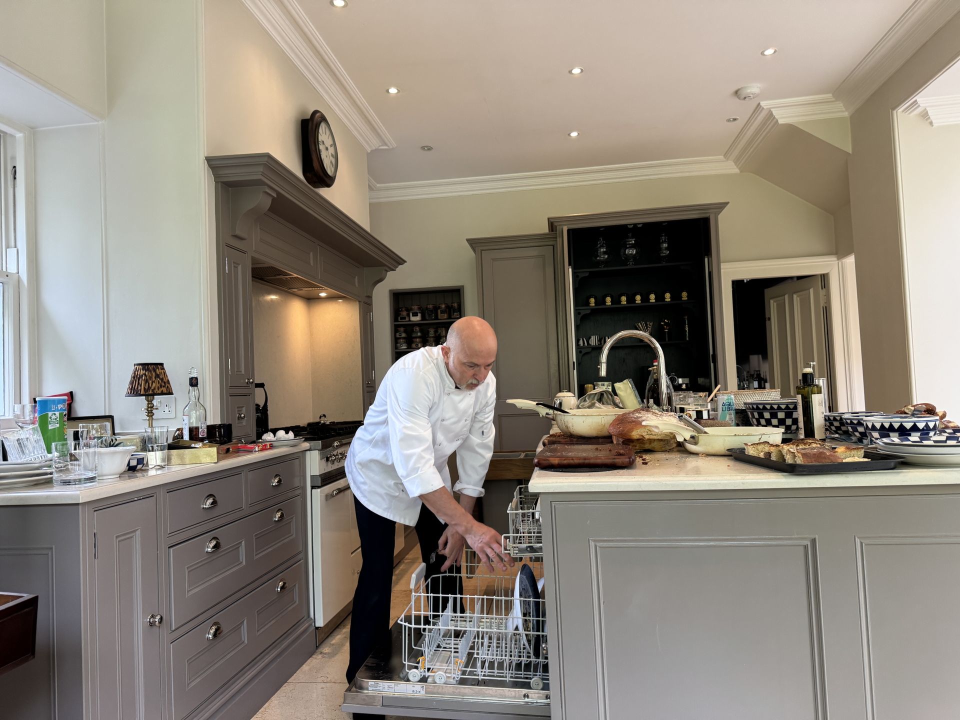 Private chef loading the dishwasher and clearing down a country house kitchen after a dinner service